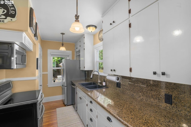 3305 NE Siskiyou St, Portland, OR 97212 - kitchen with appliances with stainless steel finishes, a sink, white cabinets, wood finished floors, and hanging light fixtures