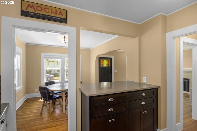 3305 NE Siskiyou St, Portland, OR 97212 - kitchen featuring wood finished floors, ornamental molding, arched walkways, dark brown cabinetry, and baseboards