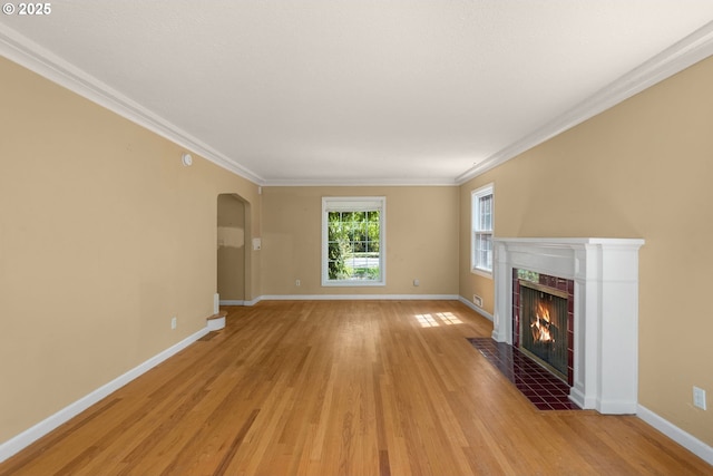 205 NE Billingher Dr, Portland, OR 97220 - unfurnished living room featuring a tile fireplace, light wood-style flooring, baseboards, and arched walkways