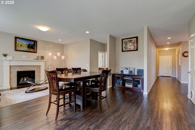 dining area featuring dark hardwood / wood-style flooring, a tiled fireplace, and a textured ceiling