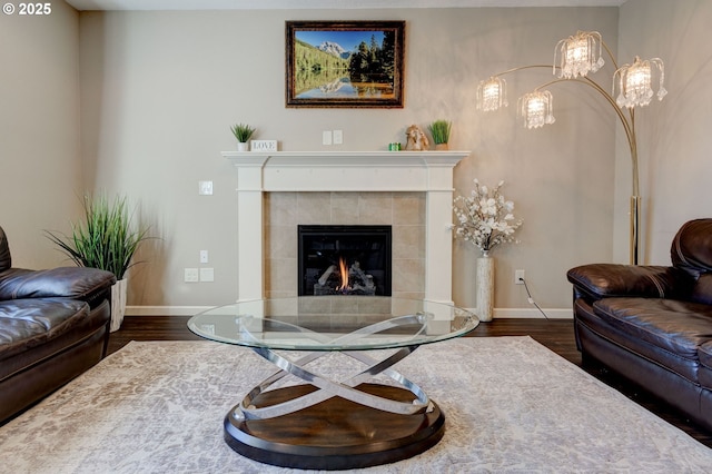 living room with a tile fireplace and dark hardwood / wood-style flooring