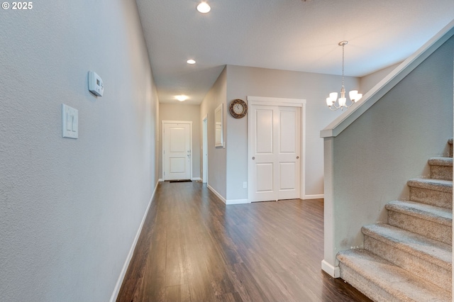 corridor with a notable chandelier and dark hardwood / wood-style floors