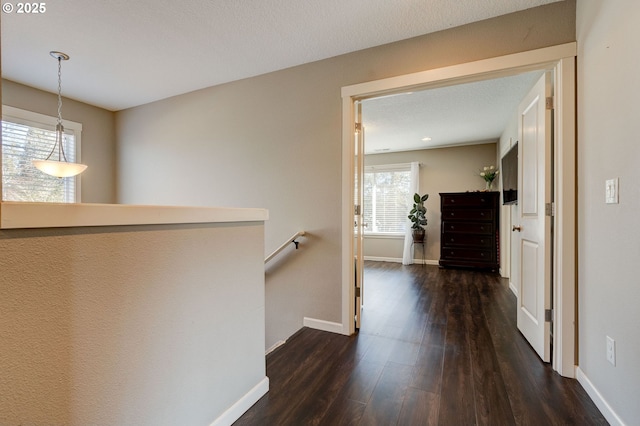 hall with dark wood-type flooring and a textured ceiling