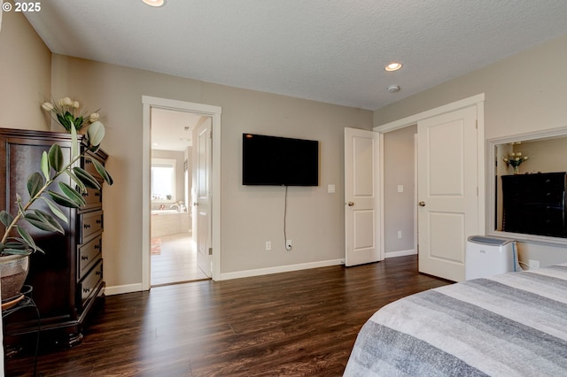 bedroom featuring ensuite bath, dark hardwood / wood-style floors, and a textured ceiling