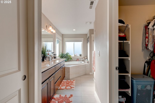 bathroom with tile patterned flooring, vanity, and tiled bath