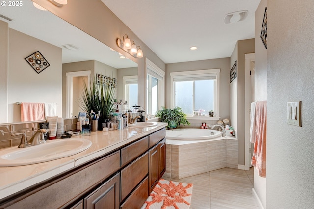 bathroom with vanity, tiled bath, and tile patterned flooring