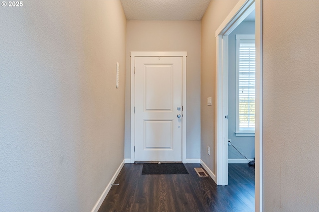 doorway to outside featuring dark wood-type flooring and a textured ceiling