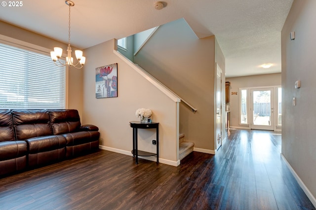 living room with an inviting chandelier, dark hardwood / wood-style floors, and a textured ceiling