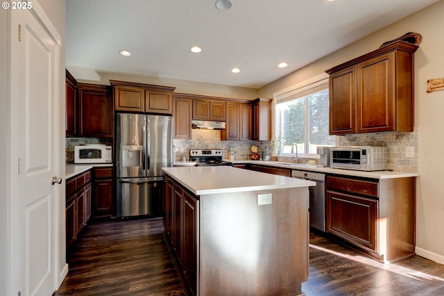 kitchen with sink, a kitchen island, dark hardwood / wood-style floors, and appliances with stainless steel finishes