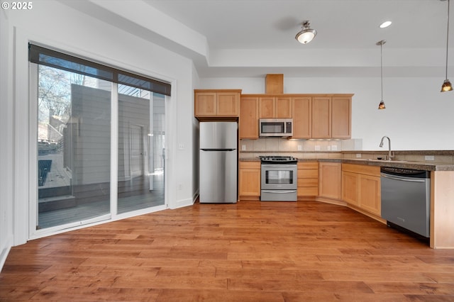 kitchen featuring decorative backsplash, hanging light fixtures, light hardwood / wood-style floors, stainless steel appliances, and light brown cabinets