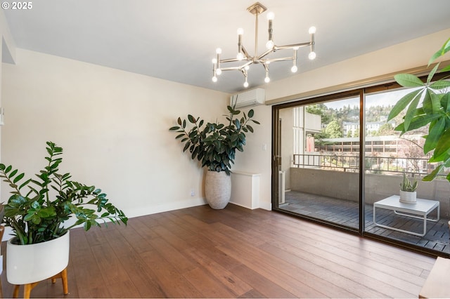 interior space with baseboards, wood-type flooring, a notable chandelier, and an AC wall unit