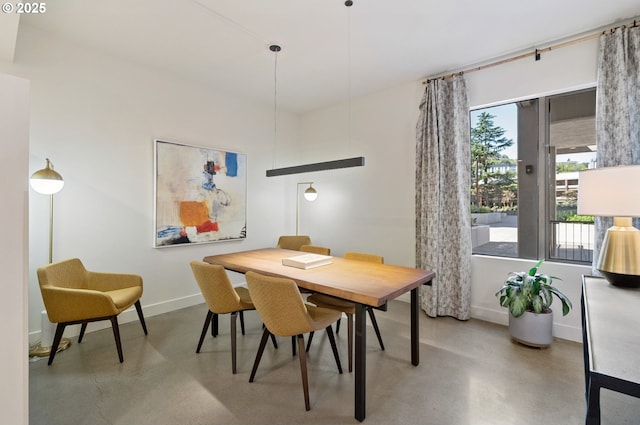 dining room featuring baseboards and concrete flooring