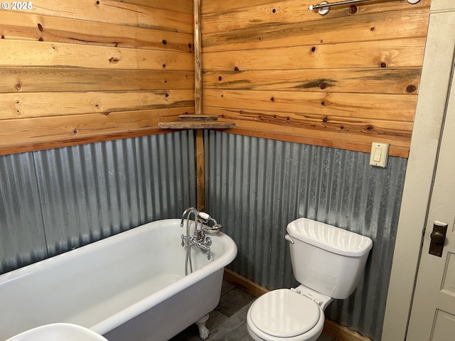 bathroom with toilet, a freestanding tub, wood finished floors, and baseboards