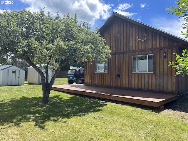 view of side of property with a storage shed, an outbuilding, a lawn, and a deck