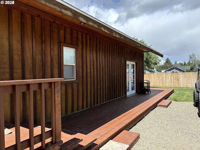 view of home's exterior with a deck, french doors, and fence