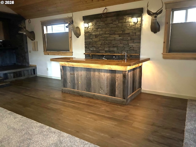 indoor wet bar featuring baseboards, dark wood-style flooring, healthy amount of natural light, a fireplace, and vaulted ceiling