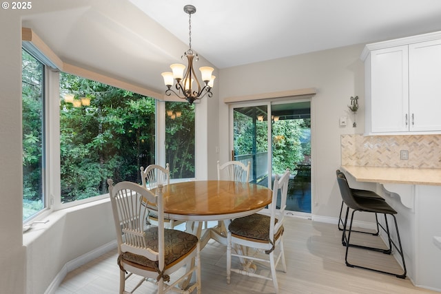 dining room with an inviting chandelier, light wood-style floors, baseboards, and a wealth of natural light