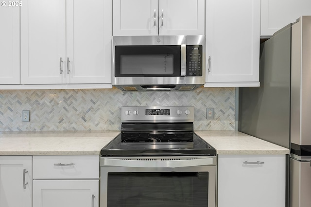 kitchen featuring light stone counters, decorative backsplash, white cabinetry, and stainless steel appliances