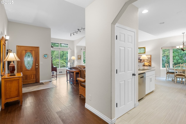 entrance foyer featuring an inviting chandelier, baseboards, light wood-type flooring, and track lighting