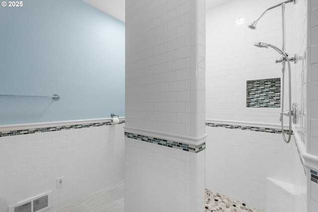 bathroom featuring visible vents, a stall shower, and tile walls