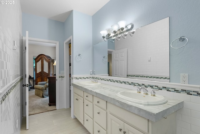 full bath with a sink, backsplash, tile walls, and double vanity