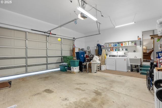 garage with a garage door opener, separate washer and dryer, and a sink