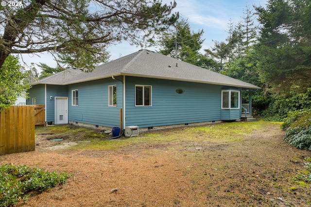 rear view of property featuring crawl space, roof with shingles, and fence