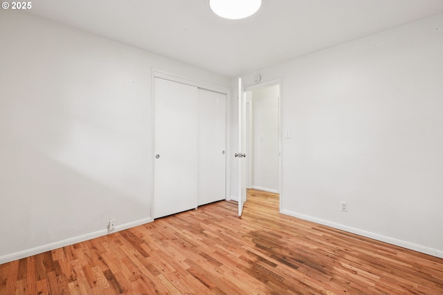 unfurnished bedroom featuring baseboards, a closet, and light wood-type flooring