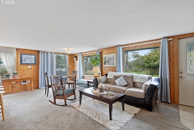 living area with light carpet, wooden walls, and a healthy amount of sunlight