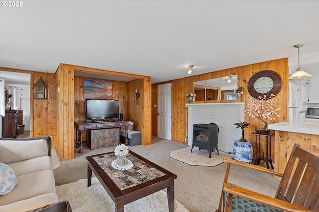 carpeted living room featuring a wood stove and wooden walls