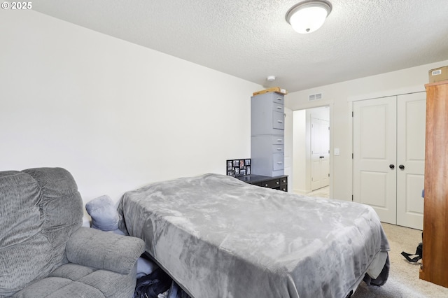 bedroom with light carpet, a textured ceiling, visible vents, and a closet