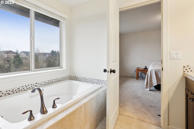 ensuite bathroom featuring a relaxing tiled tub, tile patterned flooring, vanity, and ensuite bathroom