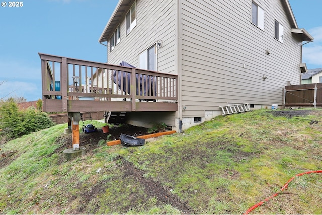 view of side of property with a deck, a lawn, and fence