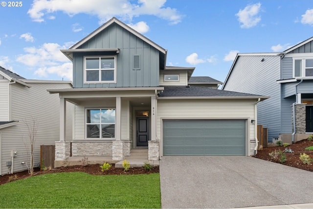 view of front of house with a front yard, stone siding, a garage, aphalt driveway, and board and batten siding