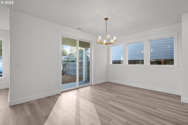 unfurnished dining area featuring a notable chandelier, hardwood / wood-style flooring, and a healthy amount of sunlight