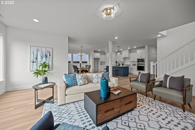 living room featuring recessed lighting, baseboards, stairs, and light wood finished floors