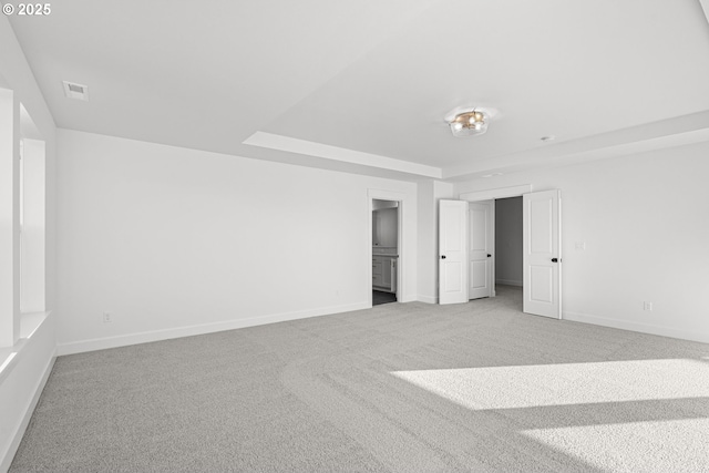 unfurnished bedroom featuring a tray ceiling and carpet floors