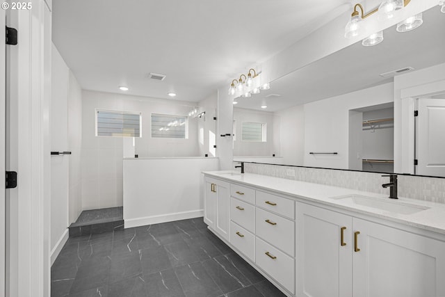 bathroom featuring vanity, decorative backsplash, and tiled shower