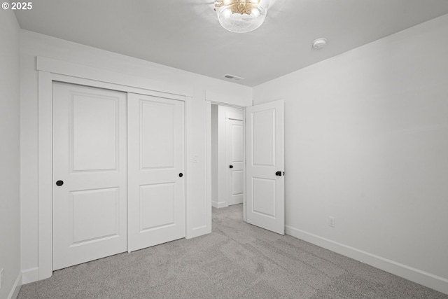 unfurnished bedroom with light colored carpet and a closet