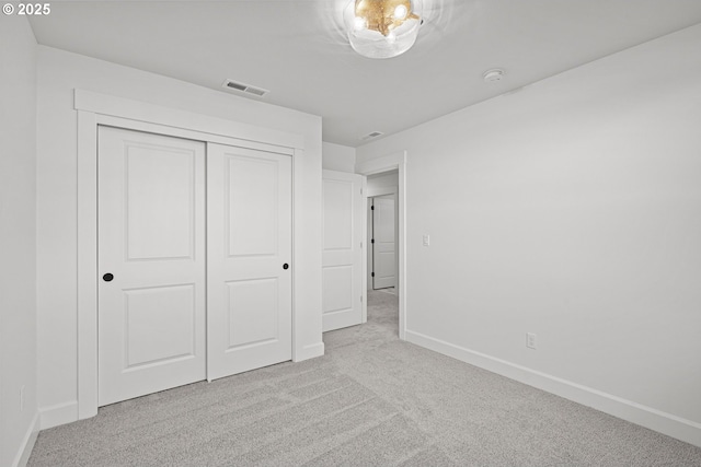 unfurnished bedroom featuring light carpet and a closet