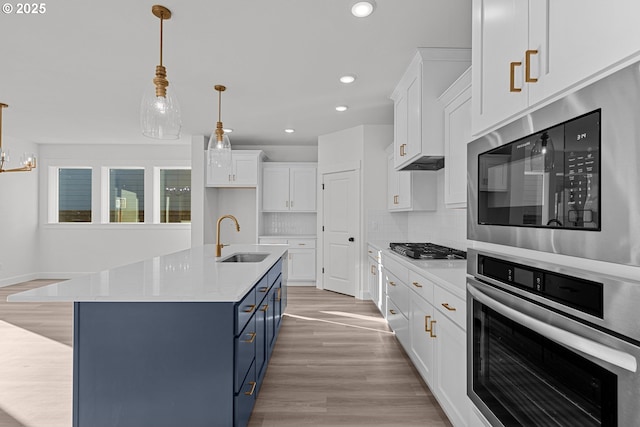 kitchen with stainless steel appliances, white cabinetry, sink, and blue cabinets