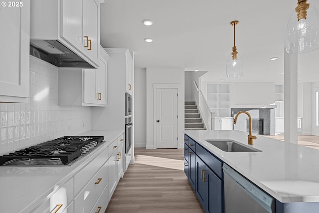 kitchen with sink, hanging light fixtures, stainless steel appliances, light stone counters, and white cabinets