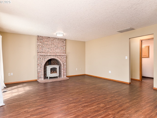 unfurnished living room with a textured ceiling, visible vents, and wood finished floors