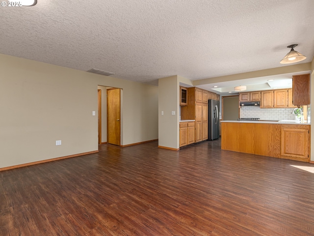 unfurnished living room featuring visible vents, baseboards, dark wood-type flooring, a textured ceiling, and a sink