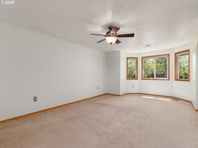 spare room featuring baseboards, plenty of natural light, a ceiling fan, and light colored carpet