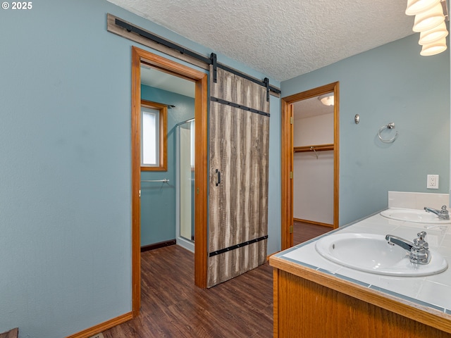 bathroom with wood finished floors, a sink, a textured ceiling, and a stall shower