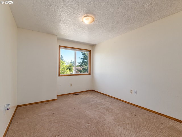unfurnished room featuring light colored carpet, a textured ceiling, and baseboards