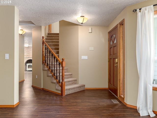 foyer entrance featuring dark wood-type flooring, a textured ceiling, and stairway