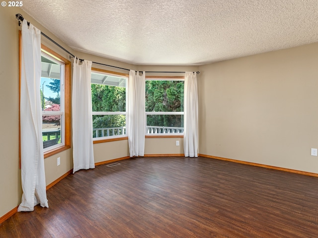 unfurnished room with baseboards, a wealth of natural light, and wood finished floors