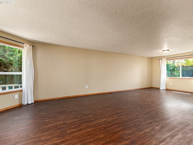 spare room featuring baseboards, a textured ceiling, and dark wood finished floors